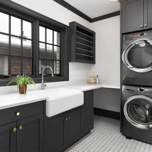 Sydney laundry renovation – WizBuilt modern Sydney laundry renovation with black cabinetry, farmhouse sink and stacked washer dryer